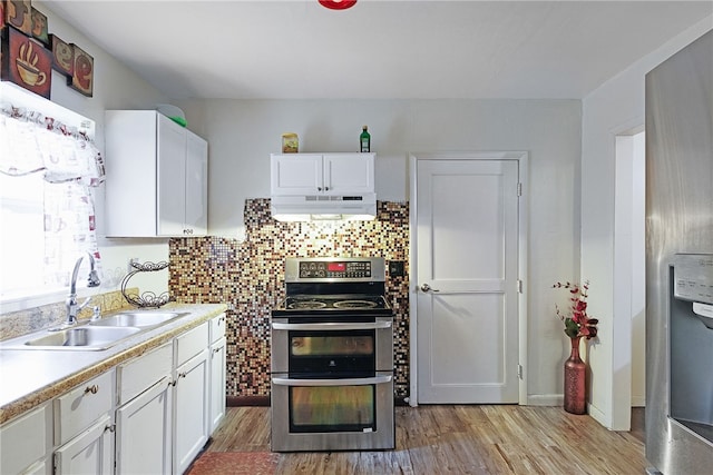 kitchen with white cabinets, sink, tasteful backsplash, stainless steel range, and light hardwood / wood-style flooring