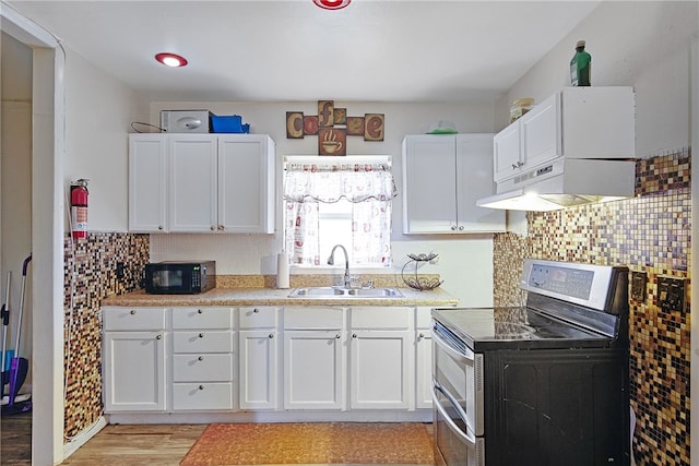 kitchen with light wood-type flooring, stainless steel range with electric cooktop, sink, and white cabinets