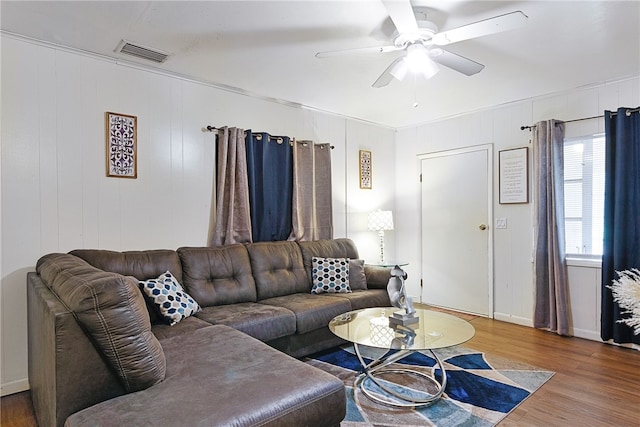 living room featuring wooden walls, hardwood / wood-style floors, and ceiling fan