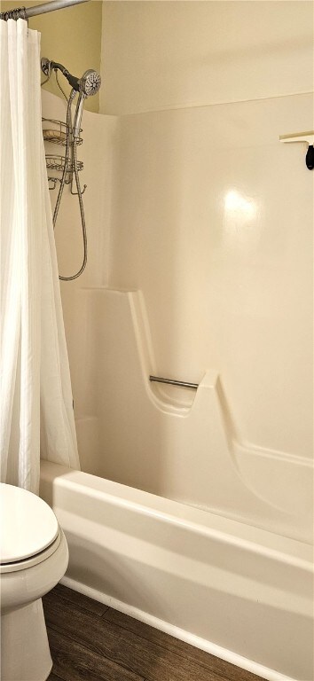 bathroom featuring toilet, wood-type flooring, and shower / tub combo with curtain