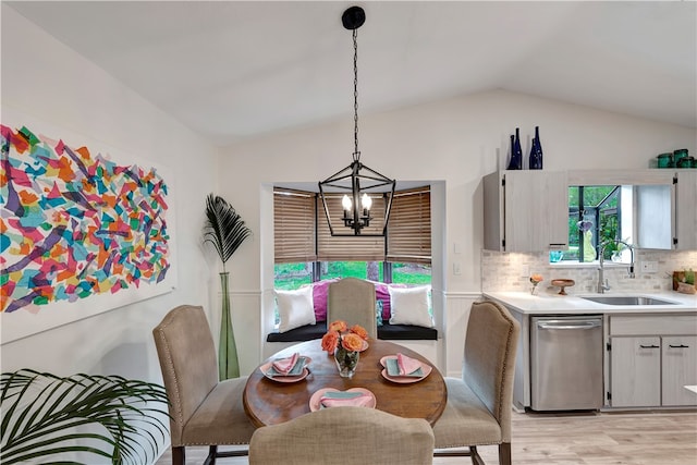 dining area featuring light hardwood / wood-style floors, sink, lofted ceiling, and an inviting chandelier