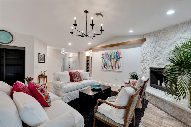 living room featuring lofted ceiling, a notable chandelier, a stone fireplace, and light hardwood / wood-style floors