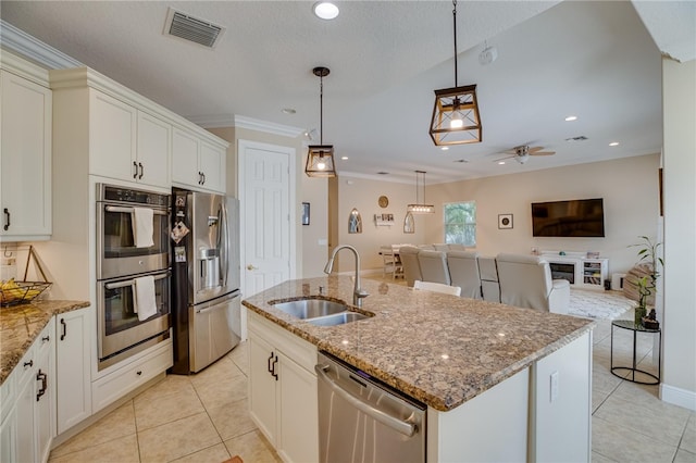 kitchen featuring pendant lighting, a kitchen island with sink, sink, ornamental molding, and stainless steel appliances