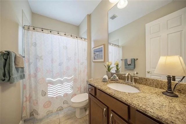 bathroom with toilet, vanity, and tile patterned floors