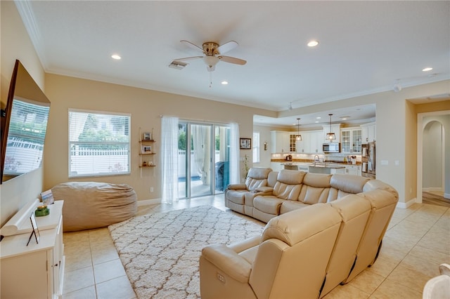 tiled living room with ceiling fan and crown molding