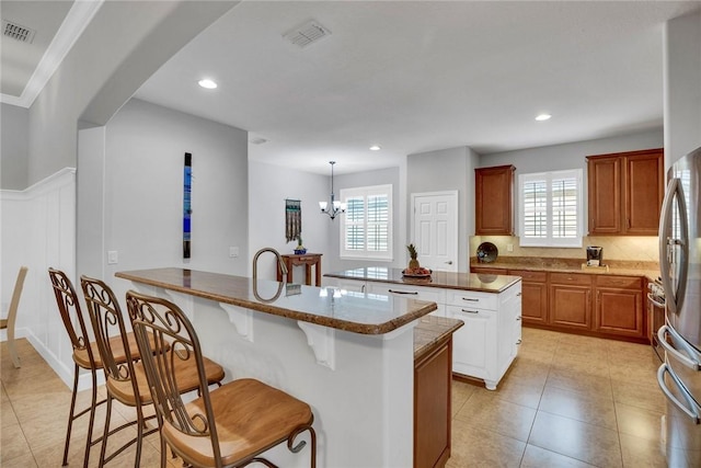 kitchen featuring stainless steel refrigerator, a center island, hanging light fixtures, plenty of natural light, and a chandelier