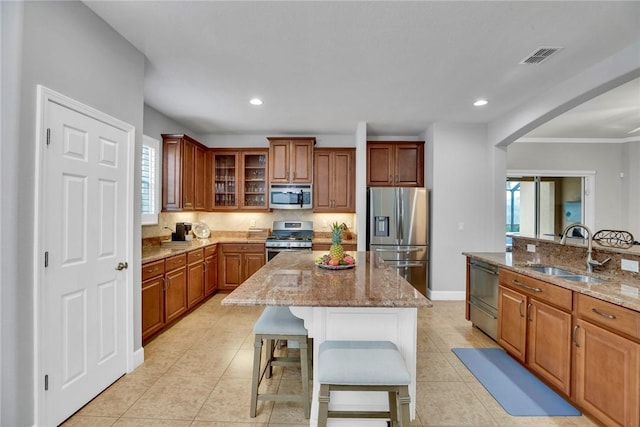 kitchen featuring sink, light stone countertops, a kitchen island, a kitchen bar, and stainless steel appliances