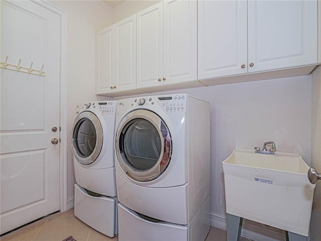 laundry room featuring cabinets, sink, light tile patterned flooring, and washing machine and clothes dryer