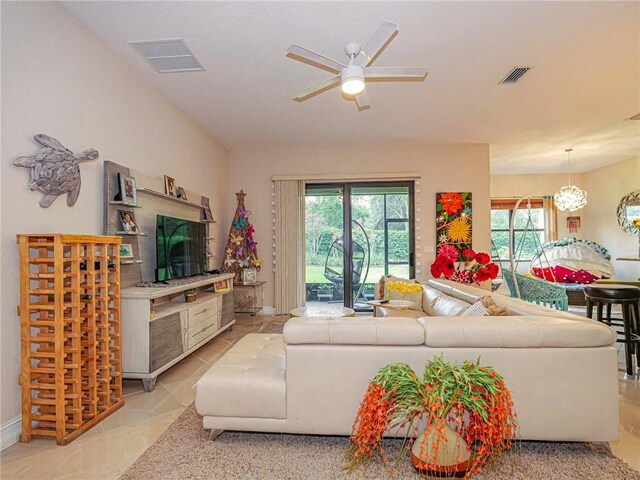 living room with ceiling fan with notable chandelier and plenty of natural light