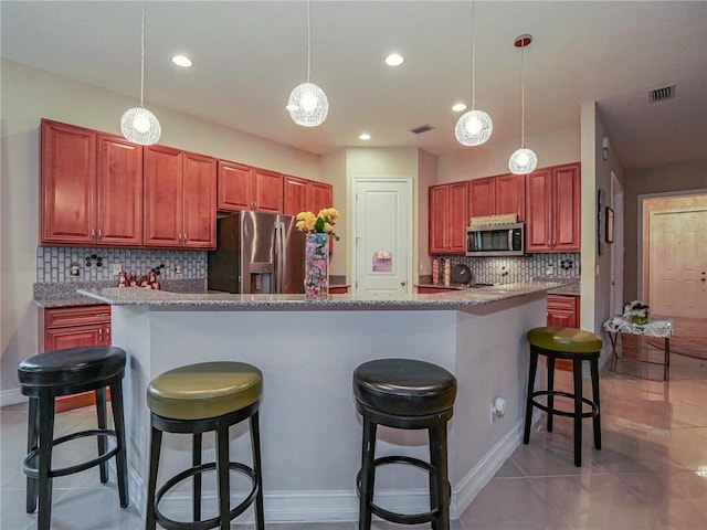 kitchen featuring tasteful backsplash, a center island, pendant lighting, and appliances with stainless steel finishes