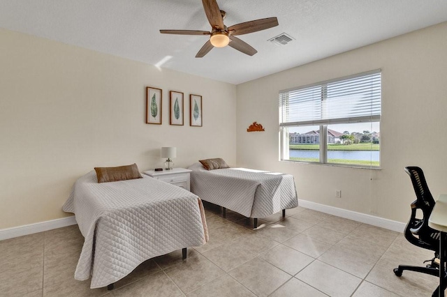 bedroom with ceiling fan, a water view, and light tile patterned floors