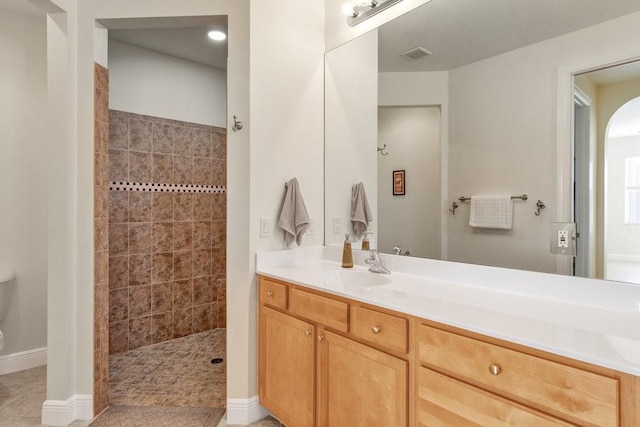 bathroom featuring tiled shower, vanity, and tile patterned flooring