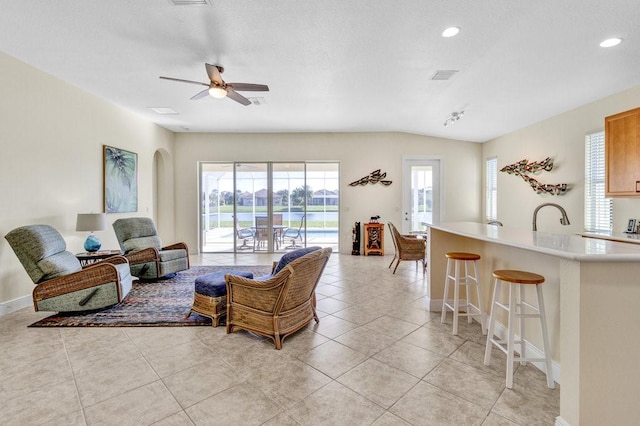 tiled living room with ceiling fan, lofted ceiling, and sink