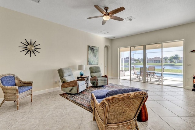 sitting room featuring ceiling fan, a water view, and light tile patterned floors