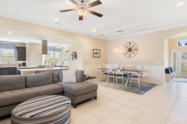 living room featuring ceiling fan, ornamental molding, sink, and light tile patterned floors