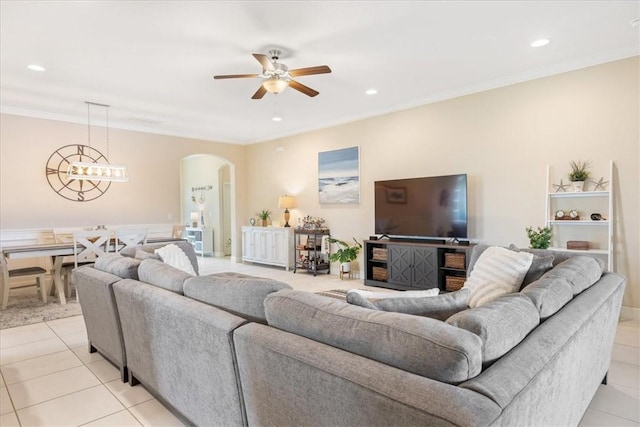 tiled living room with ceiling fan with notable chandelier and ornamental molding