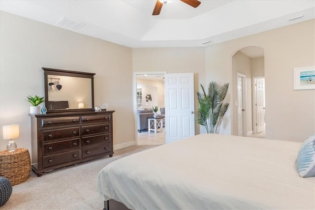 bedroom featuring a raised ceiling, ceiling fan, and light carpet