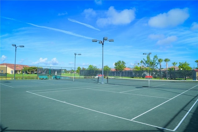 view of tennis court with community basketball court and fence
