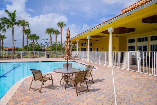 pool with fence, a ceiling fan, and a patio area