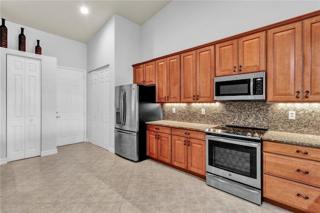 kitchen with brown cabinetry, appliances with stainless steel finishes, and tasteful backsplash