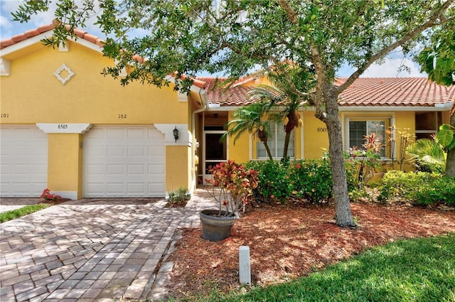 view of front of property with a garage, stucco siding, decorative driveway, and a tiled roof