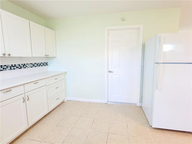 kitchen with white cabinets, backsplash, white refrigerator, and light tile patterned floors