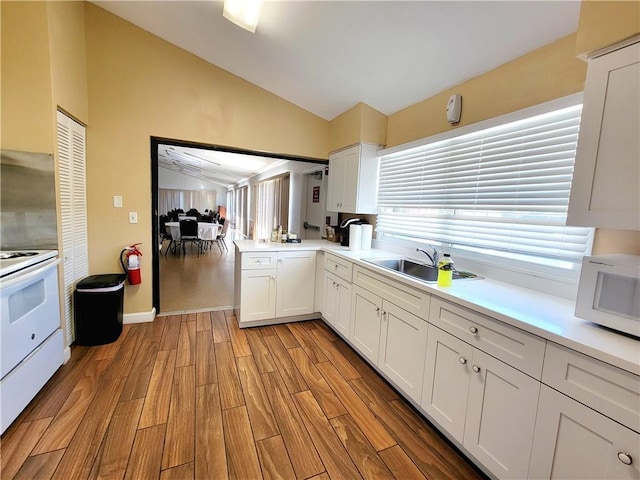 kitchen with sink, white appliances, white cabinets, and lofted ceiling