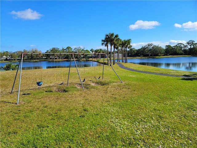 exterior space featuring a playground, a lawn, and a water view