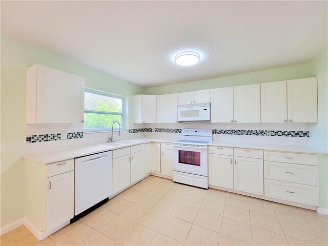 kitchen with white appliances, white cabinetry, decorative backsplash, sink, and light tile patterned flooring