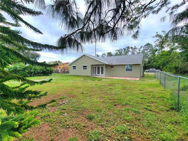 rear view of house with french doors and a lawn