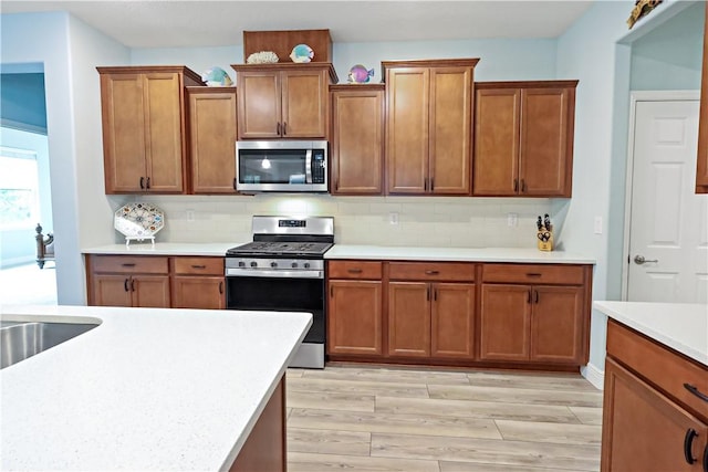 kitchen with stainless steel appliances, decorative backsplash, and light wood-type flooring