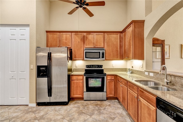 kitchen featuring light stone counters, stainless steel appliances, ceiling fan, sink, and light tile patterned floors