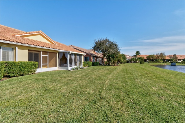 view of yard with a sunroom and a water view