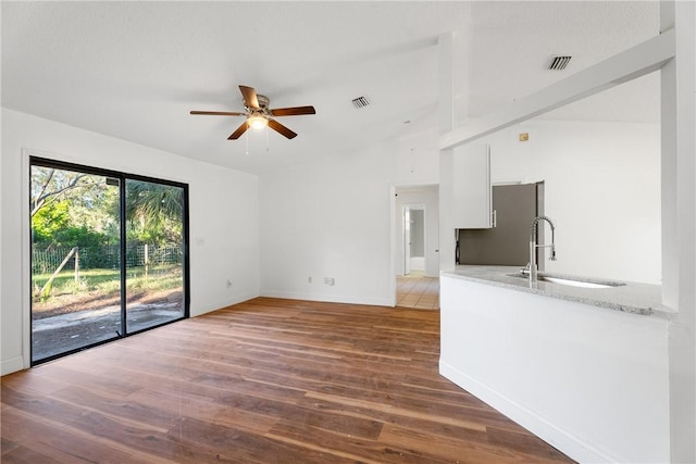 unfurnished living room with sink, beam ceiling, dark hardwood / wood-style floors, and ceiling fan