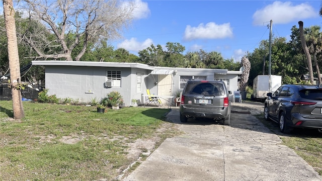 ranch-style home featuring a front yard, concrete block siding, and driveway