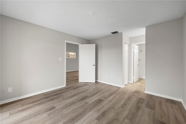 spare room with a textured ceiling and light wood-type flooring