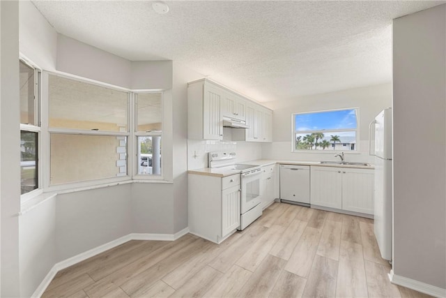 kitchen featuring sink, tasteful backsplash, light wood-type flooring, white appliances, and white cabinets