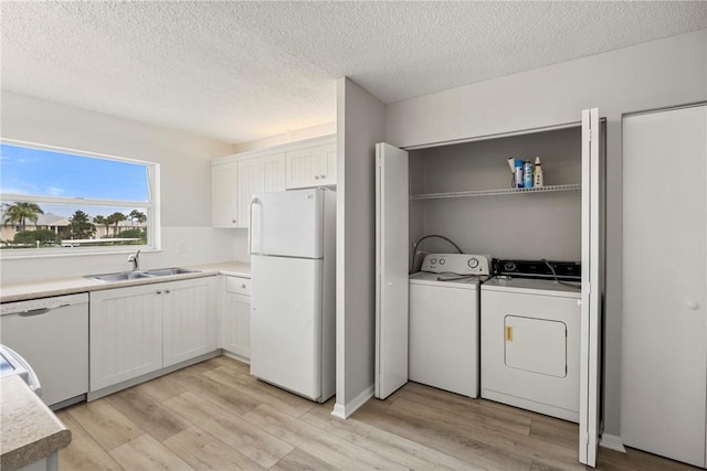 laundry area with sink, light hardwood / wood-style flooring, washer and dryer, and a textured ceiling