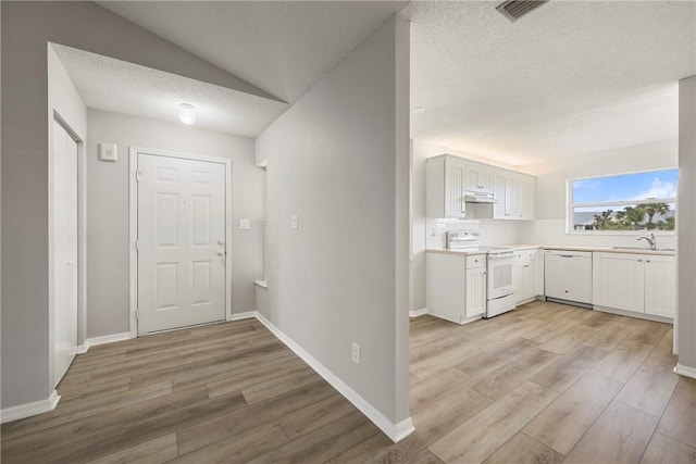 interior space with white appliances, lofted ceiling, sink, and white cabinets