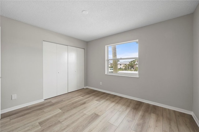 unfurnished bedroom featuring light hardwood / wood-style flooring, a closet, and a textured ceiling