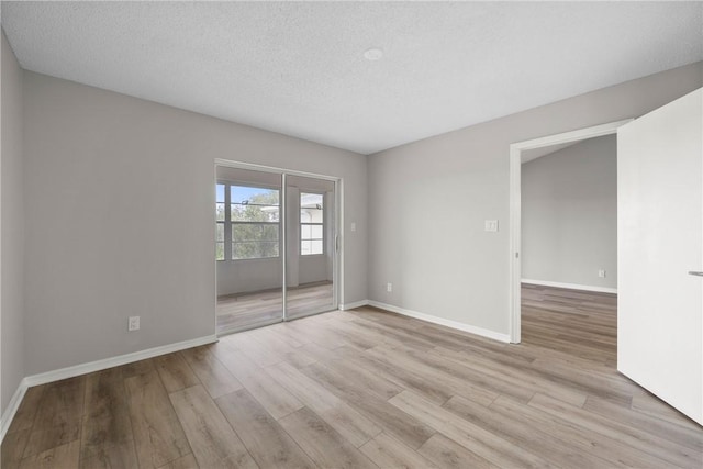 empty room with a textured ceiling and light hardwood / wood-style floors