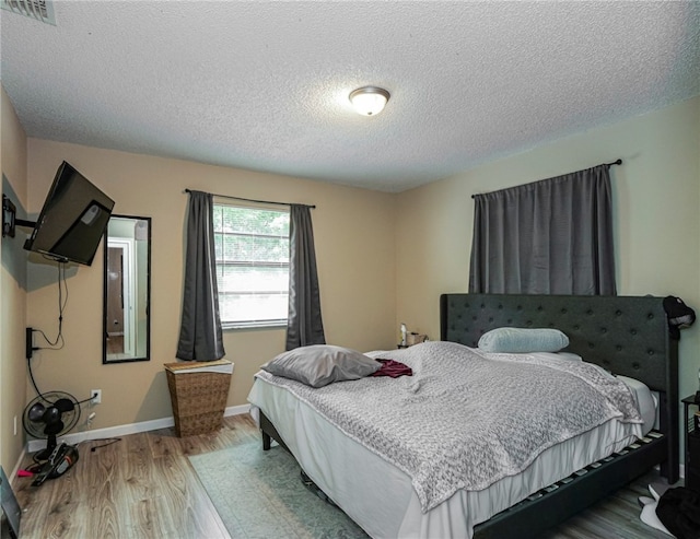 bedroom with light wood-type flooring and a textured ceiling