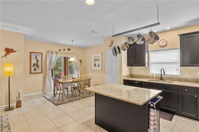 kitchen with pendant lighting, sink, light stone counters, and a kitchen island