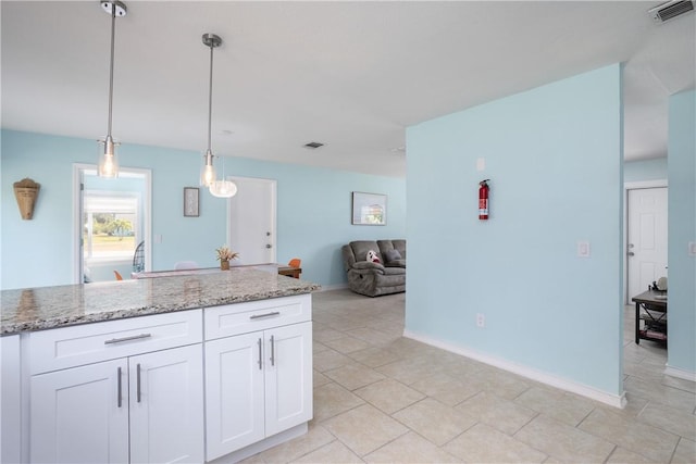 1203 Linmoor Cir NE, Palm Bay, FL 32907 - kitchen featuring light stone counters, white cabinets, hanging light fixtures, open floor plan, and baseboards