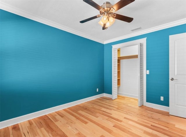 unfurnished bedroom featuring hardwood / wood-style floors, crown molding, a closet, and ceiling fan