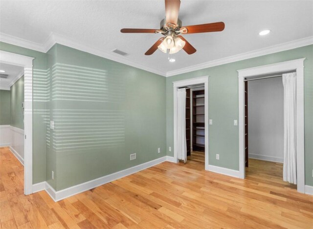 living room featuring ceiling fan, built in shelves, crown molding, and light hardwood / wood-style floors