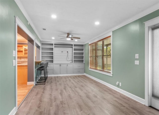 unfurnished living room featuring crown molding, ceiling fan, built in features, and light hardwood / wood-style floors