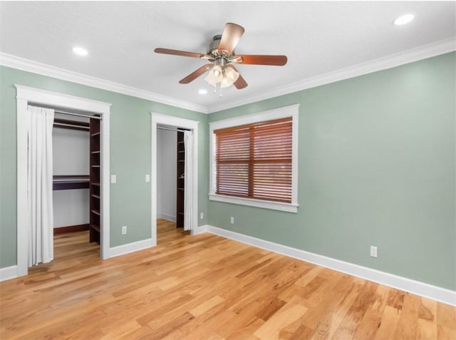 unfurnished bedroom with two closets, light hardwood / wood-style flooring, and ornamental molding