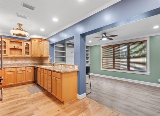 kitchen with crown molding, sink, light stone counters, and light hardwood / wood-style floors