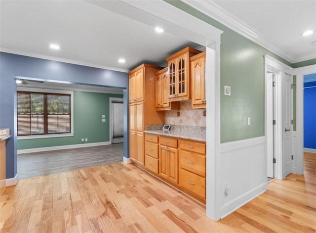 kitchen featuring light stone countertops, decorative backsplash, ornamental molding, and light hardwood / wood-style floors